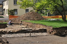 08.05.2009 - Grasnarbe, Bodenprofil am Schnitt, Mauer-/Wegreste und eine handskizzierende Archäologin / Klick vergrößert Bild